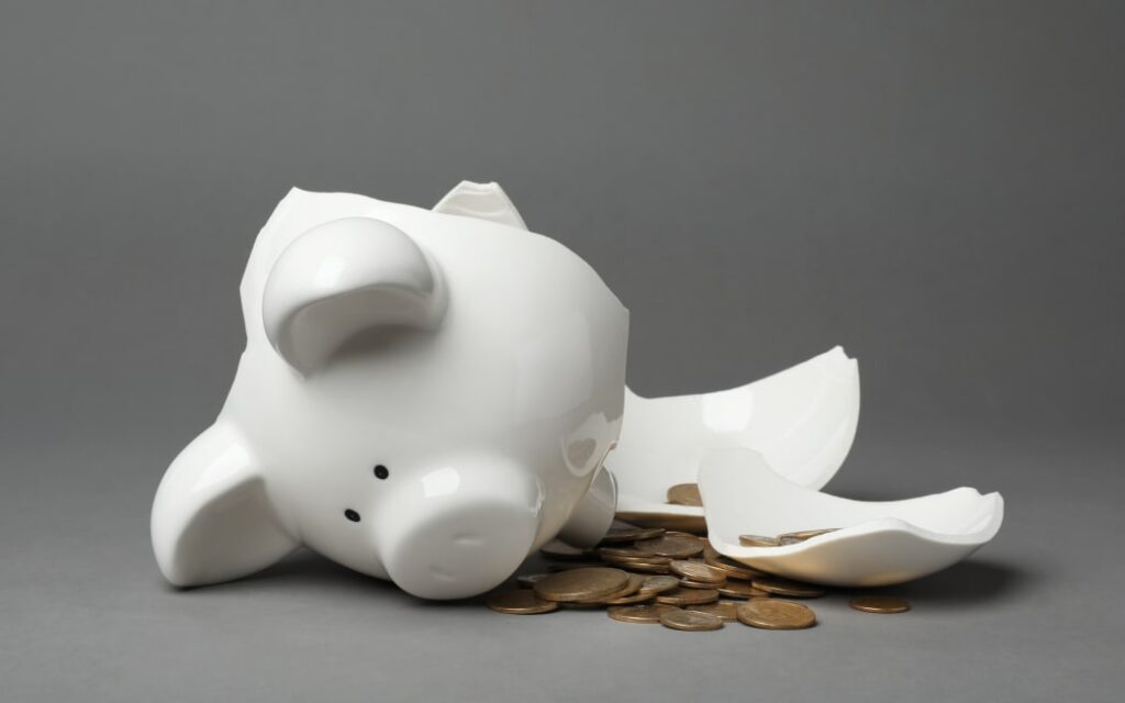 Broken piggy bank with coins on gray background